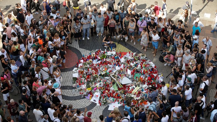 Ľudia sa zhromažďujú pri pamätníku obetiam teroristického útoku v Barcelone.