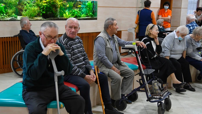 Seniori čakajú na chodbe pred miestnosťou.