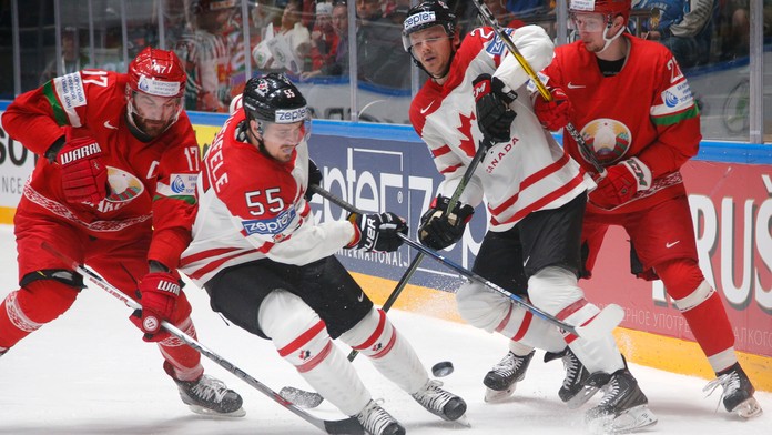 Mark Scheifele (biely vľavo) a Sam Reinhart (biely vpravo) z Kanady v súboji o puk proti dvojicie Bielorusov počas duelu na MS v