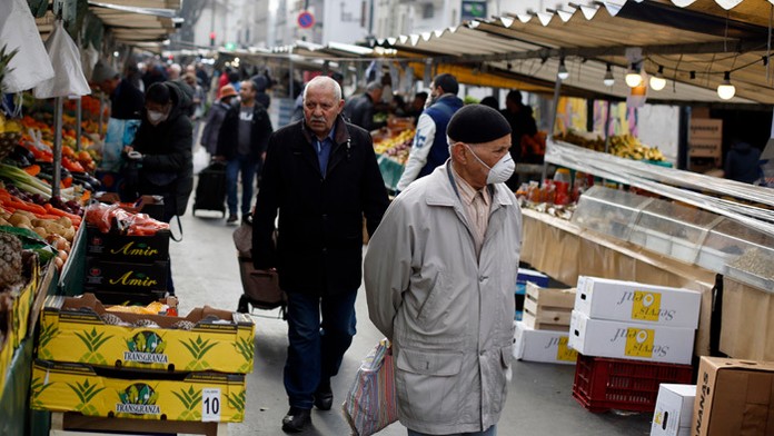 Muž s ochrannou maskou na tvári na trhu v Paríži.