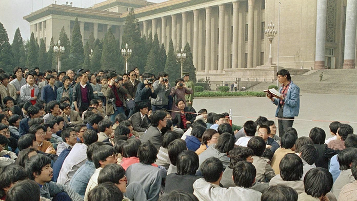 Na snímke z 18. apríla 1989 študentský líder číta zoznam požiadaviek študentom, ktorí sedia pred parlamentom v Pekingu.