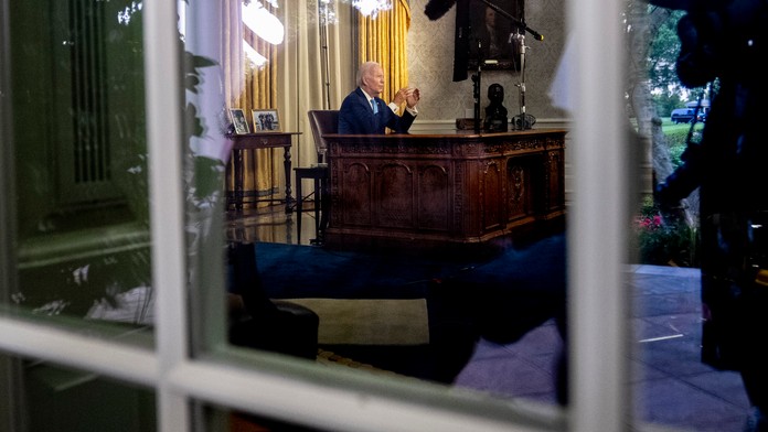 Joe Biden sedi za stolom vo svojej pracovnice v Bielom dome.