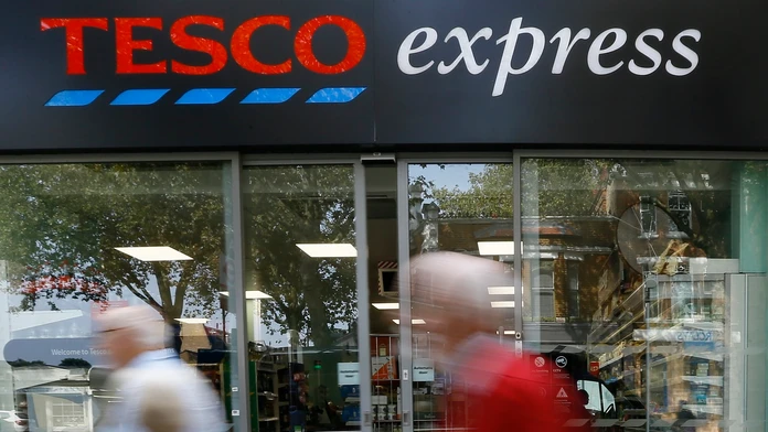 Ľudia prechádzajú okolo obchodu Tesco express.