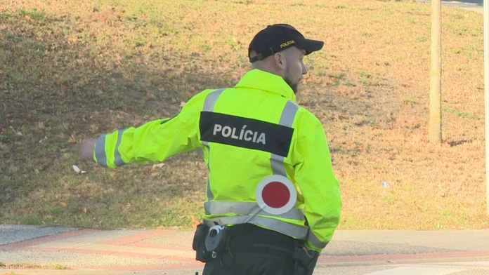 Na snímke je policajt v zltej bunde, ktory riadi dopravu. 
