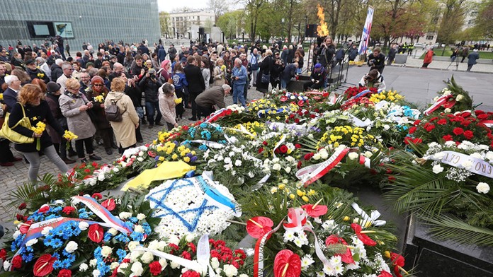 Ľudia kladú kvety počas 73. výročia začiatku povstania vo Varšavskom gete.