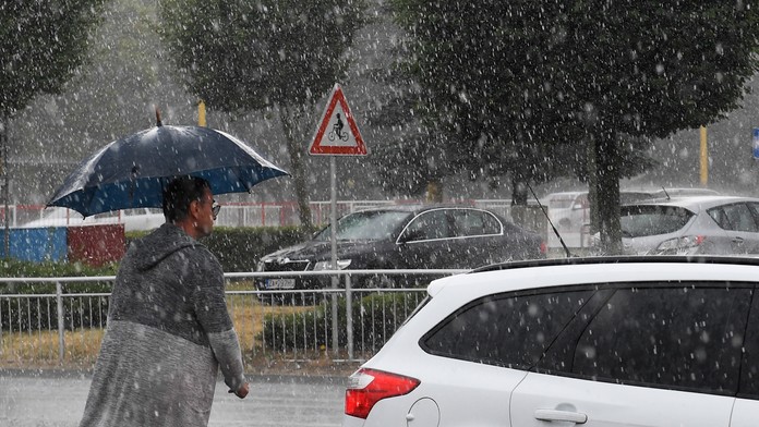 Muž s dáždnikom v ruke počas búrky.
