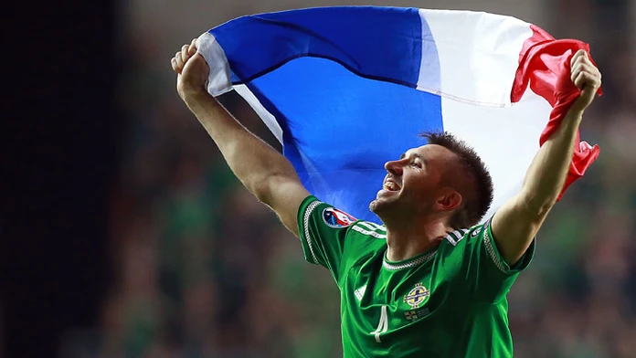 Futbalista Michael O´Neill (Severné Írsko) drží nad hlavou vlajku Francúzska po historicky premiérovom postupe na ME.  