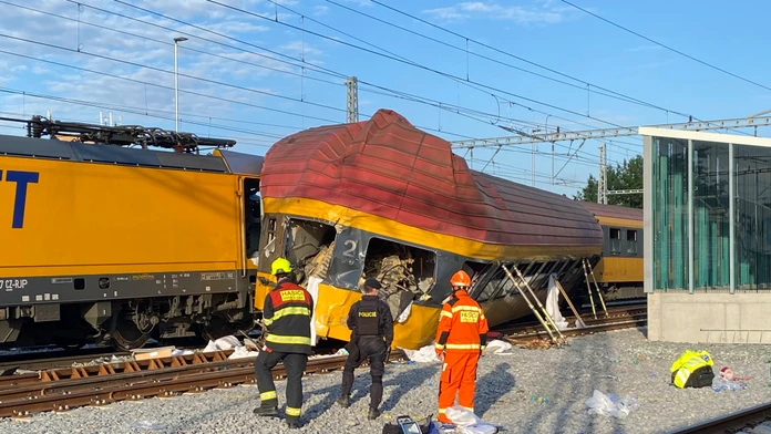 Na snímke hasiči stoja vedľa dvoch vlakov po zrážke v Pardubiciach.