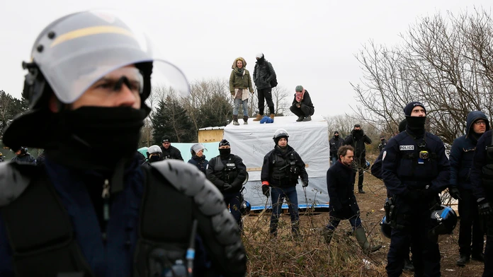 Migranti v tábore pri Calais protestujú na strechách búd.