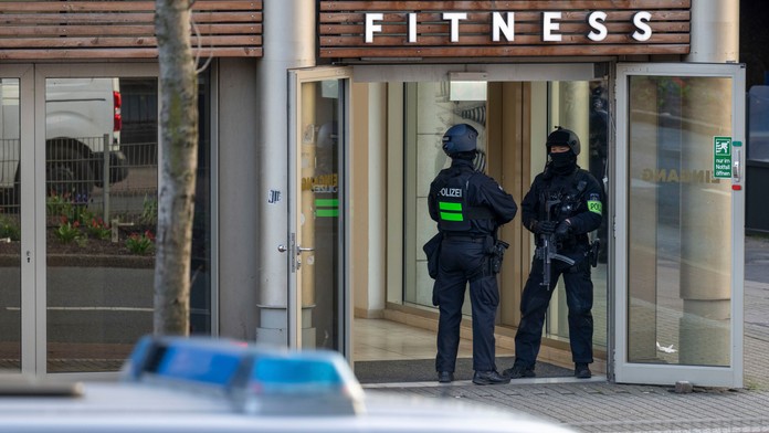Ozbrojení policajti stoja pred vstupom do fitnescentra.