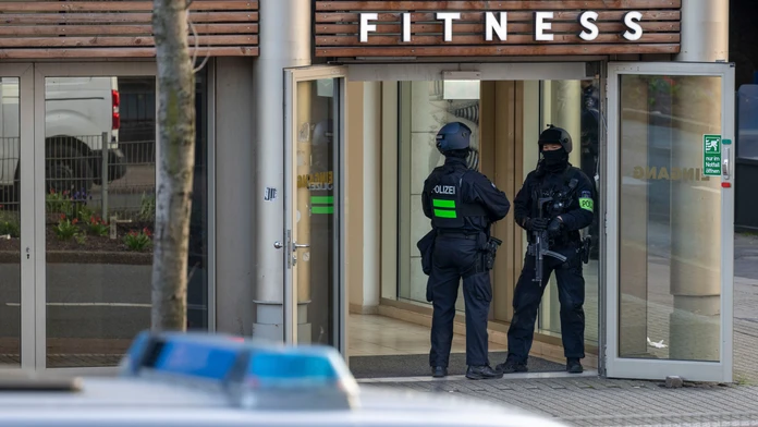Ozbrojení policajti stoja pred vstupom do fitnescentra.