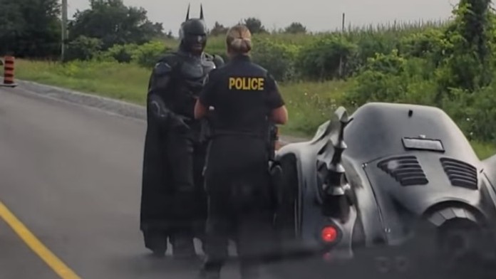 Policajtka kontroluje muža prezlečeného za Batmana.