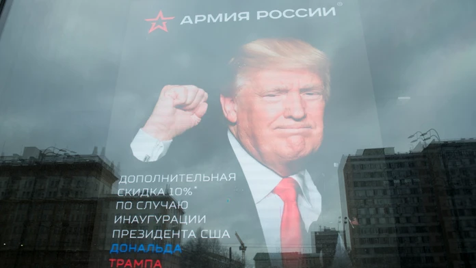 Budova veľvyslanectva USA sa odráža na okne obchodu s plagátom Donalda Trumpa v Moskve.