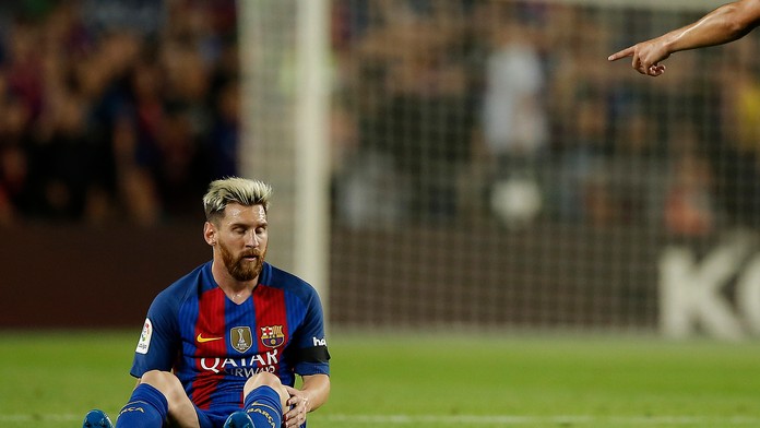 Lionel Messi sedí na trávniku 