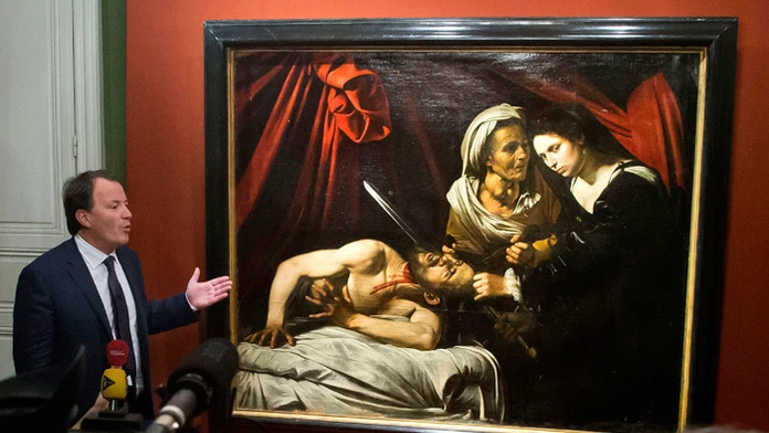 Aukčný úradník Marc Labarbe prezentuje nájdený obraz, ktorého autorom by mohol byť Caravaggio.