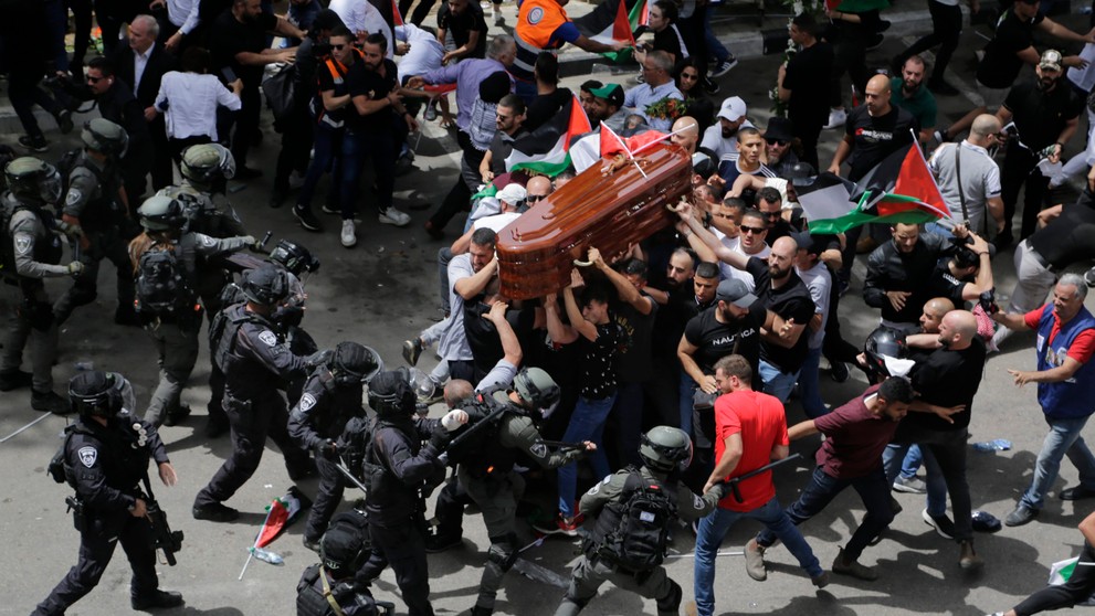 Izraelskí vojaci a policajti zasahujú proti nahnevanému davu na pohrebe novinára televízie Al Jazeera.