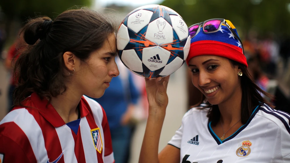 Fanúšička Realu Madrid (vpravo) a Atletica Madrid (vľavo) pózujú s futbalovou loptou pred začiatkom finále Ligy majstrov v Lisab