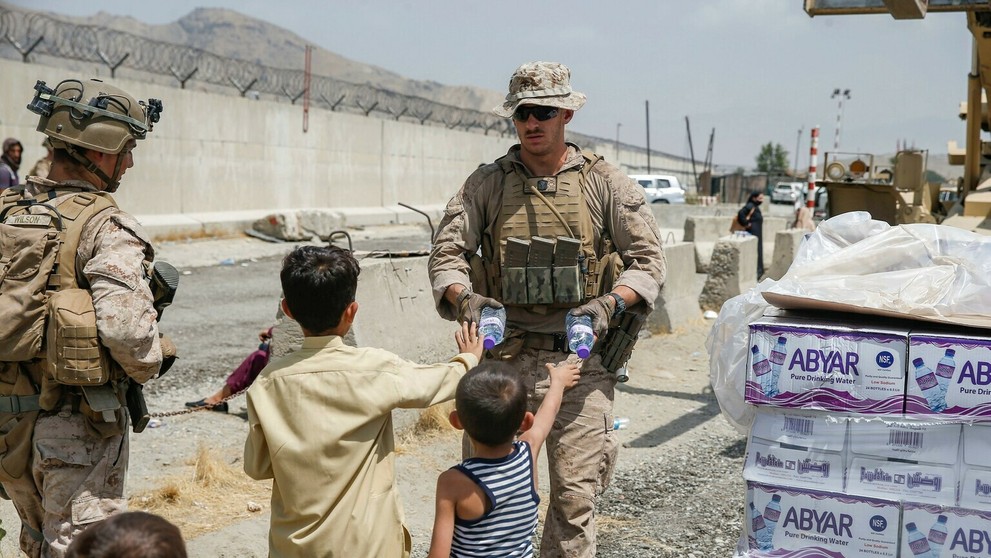 Americký vojak rozdáva afganským deťom balenú vodu.
