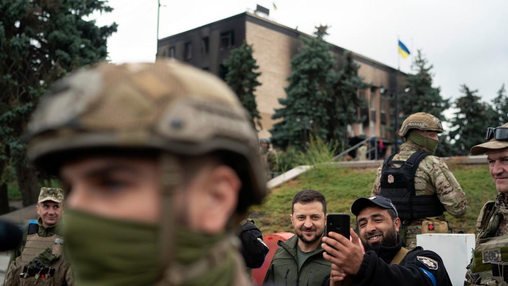 Ukrajinský prezident Volodymyr Zelenskyj pózuje pre selfie s policajtom po vztýčení ukrajinskej vlajky v ukrajinskom meste Izium 14. septembra 2022.