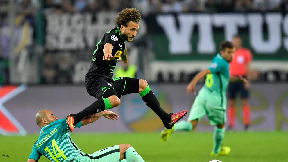 Vo výskoku hráč Borussie Mönchengladbach Fabian Johnson, na zemi v ostrom sklze defenzívna opora Barcelony Javier Mascherano v d