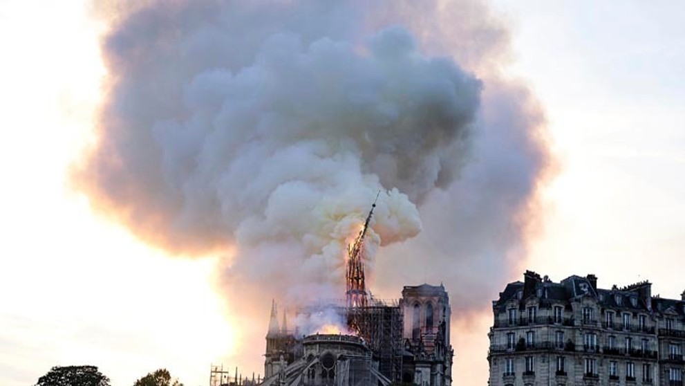 Pohľad cez zničenú klenbu hlavnej chrámovej lode na horiacu strechu Katedrály Notre-Dame.