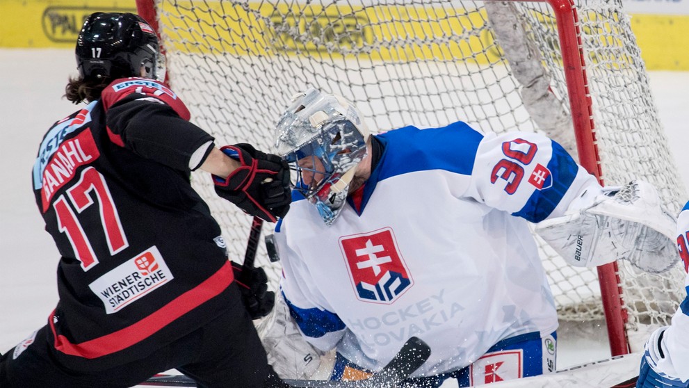 Sprava Denis Godla chytá puk pred Rakúšanom Manuelom Ganahlom v zápase Euro Hockey Challenge.