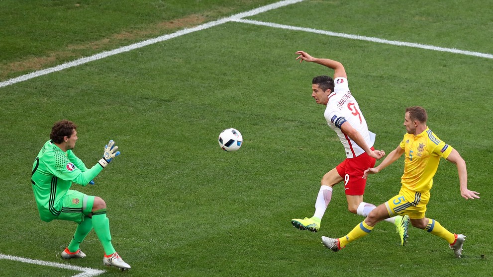 Kanonier Poľska Robert Lewandowski (druhý sprava) v šanci pred brankárom Ukrajiny Andrijom Piatovom (vľavo)