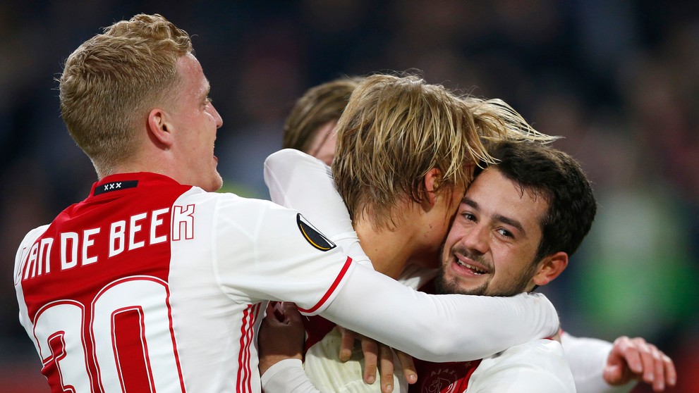 Donny van Beek (vľavo) a Amin Younes (vpravo) objímajú spoluhráča z Ajaxu Kaspara Dolberga po góle v odvete osemfinále EL proti 