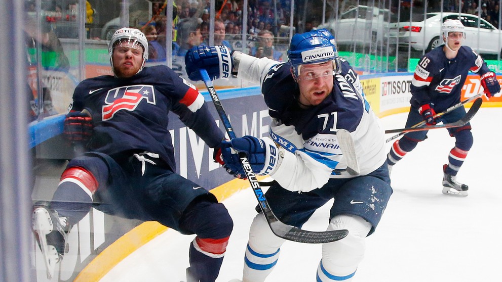 Fínsky útočník Leo Komarov (v bielom) v súboji pri mantineli proti americkému protihráčovi T.J. Compheremovi počas duelu na MS v