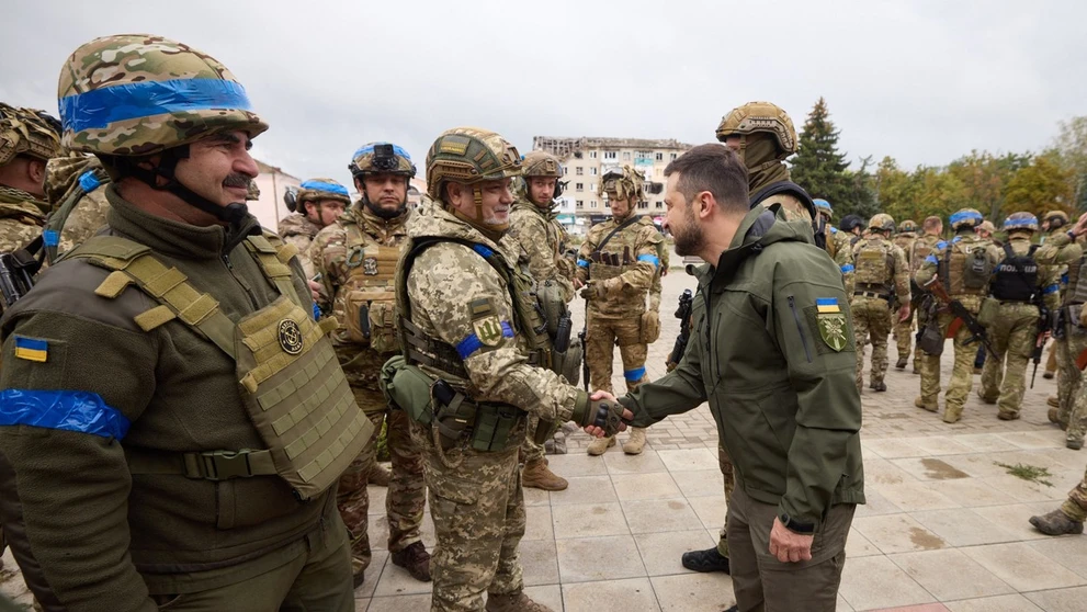 Prezident Zelenskyj si podáva ruku s ukrajinským vojakom v meste Izium.