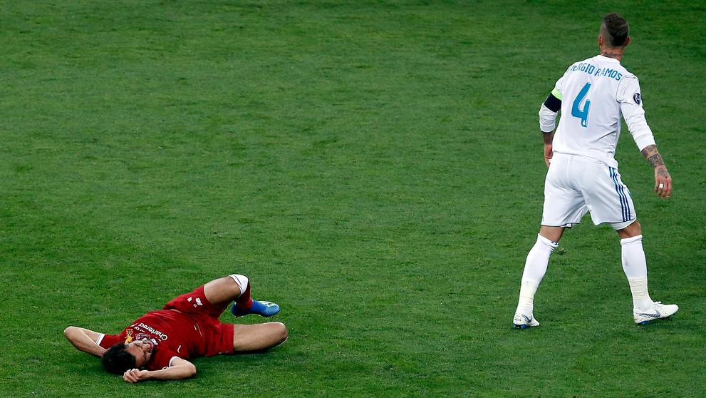 Salah leží v bolestiach na trávniku po zrážke s Ramosom.
