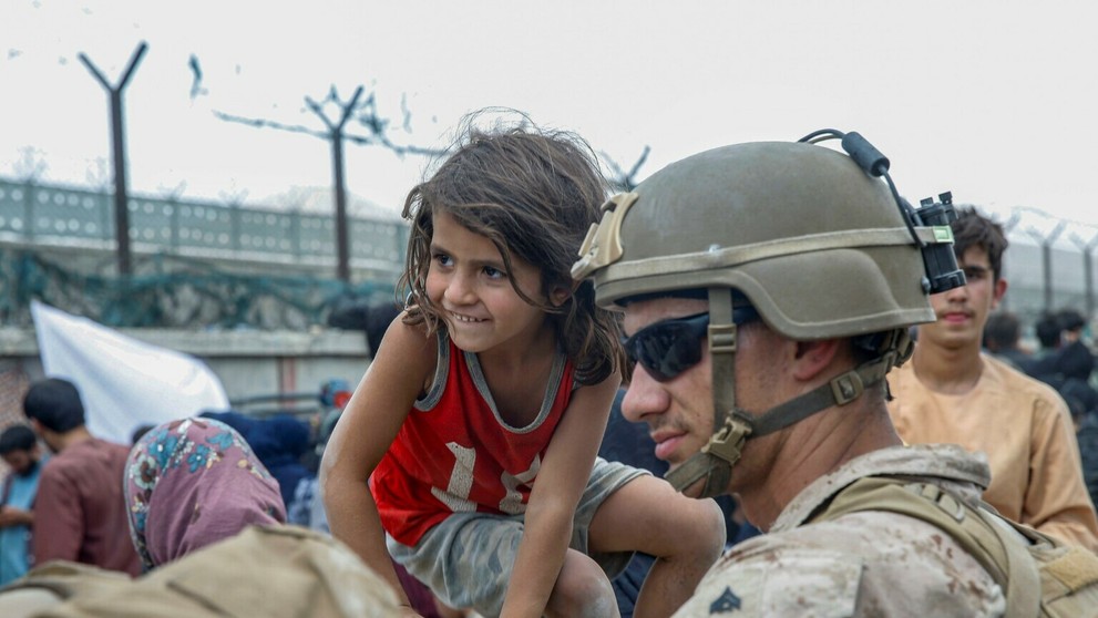 Americký vojak a afganské dievčatko čakajú spolu na evakuačné lietadlo.