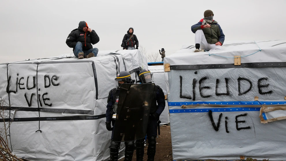 Migranti v tábore pri Calais protestujú na strechách búd.