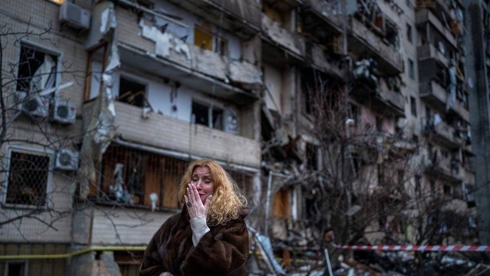 Obyvateľka Kyjeva pred zničenou bytovkou (25.2.2022)
