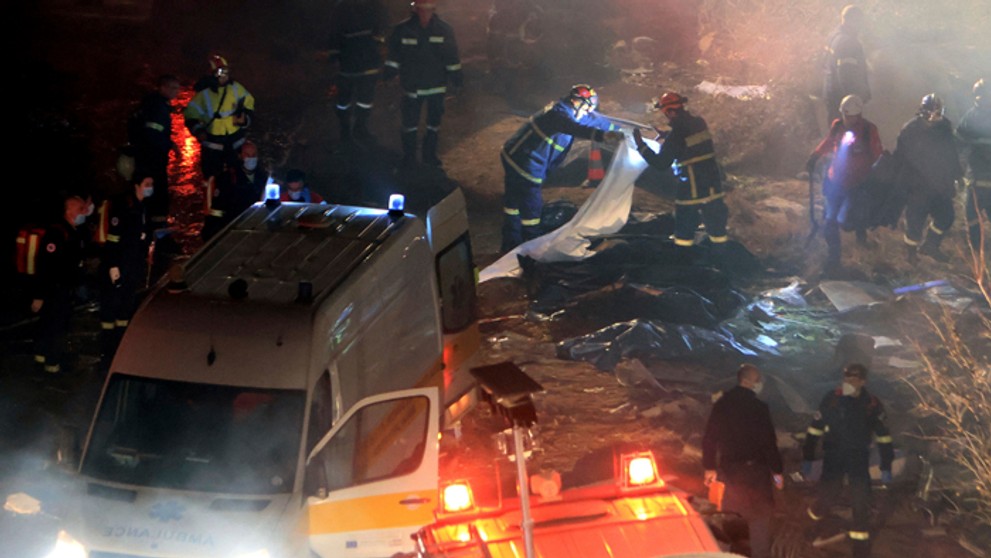 Hasiči ukladajú telá obetí na mieste zrážky nákladného a osobného vlaku v blízkosti mesta Larisa na severe Grécka.