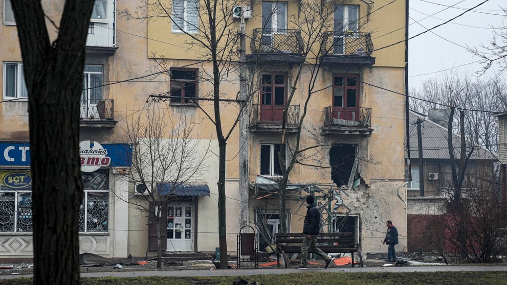 Muž prechádza okolo obytného domu zasiahnutého ostreľovaním v Mariupole na Ukrajine.