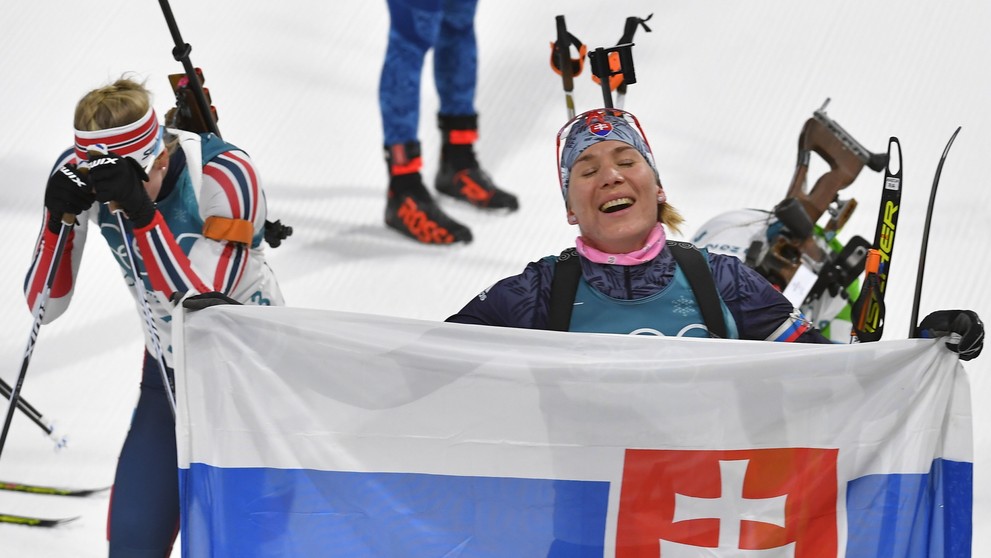 Anastasia Kuzminová drží slovenskú vlajku v cieli po zisku zlatej olympijskej medaily počas pretekov s hromadným štartom.