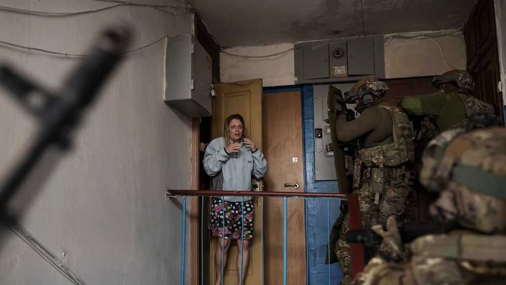 Vystrašená žena sa pozerá na príslušníkov ukrajinskej tajnej služby SBU, ktori prišli zadržať muža podozrivého z kolaborácie s Ruskom.