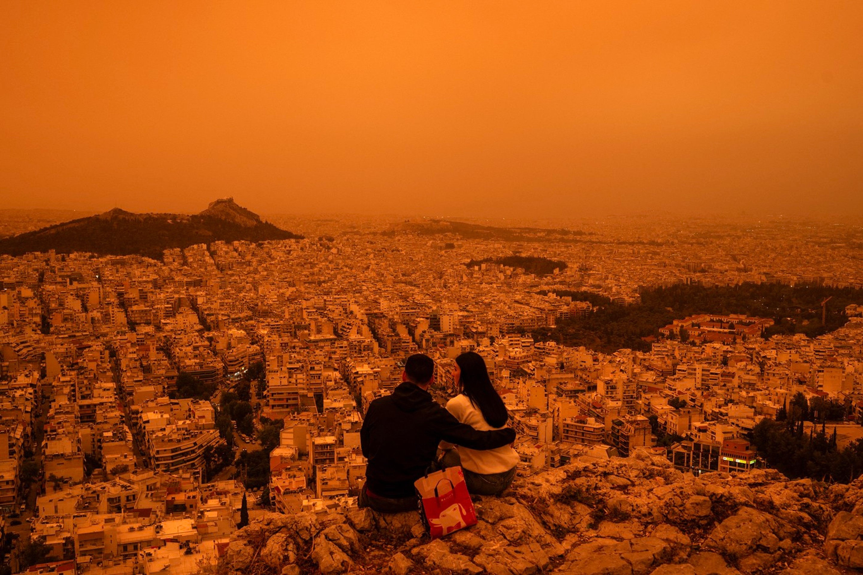 Turisti sa pozerajú na Atény zahalené do oranžovej farby saharského prachu.