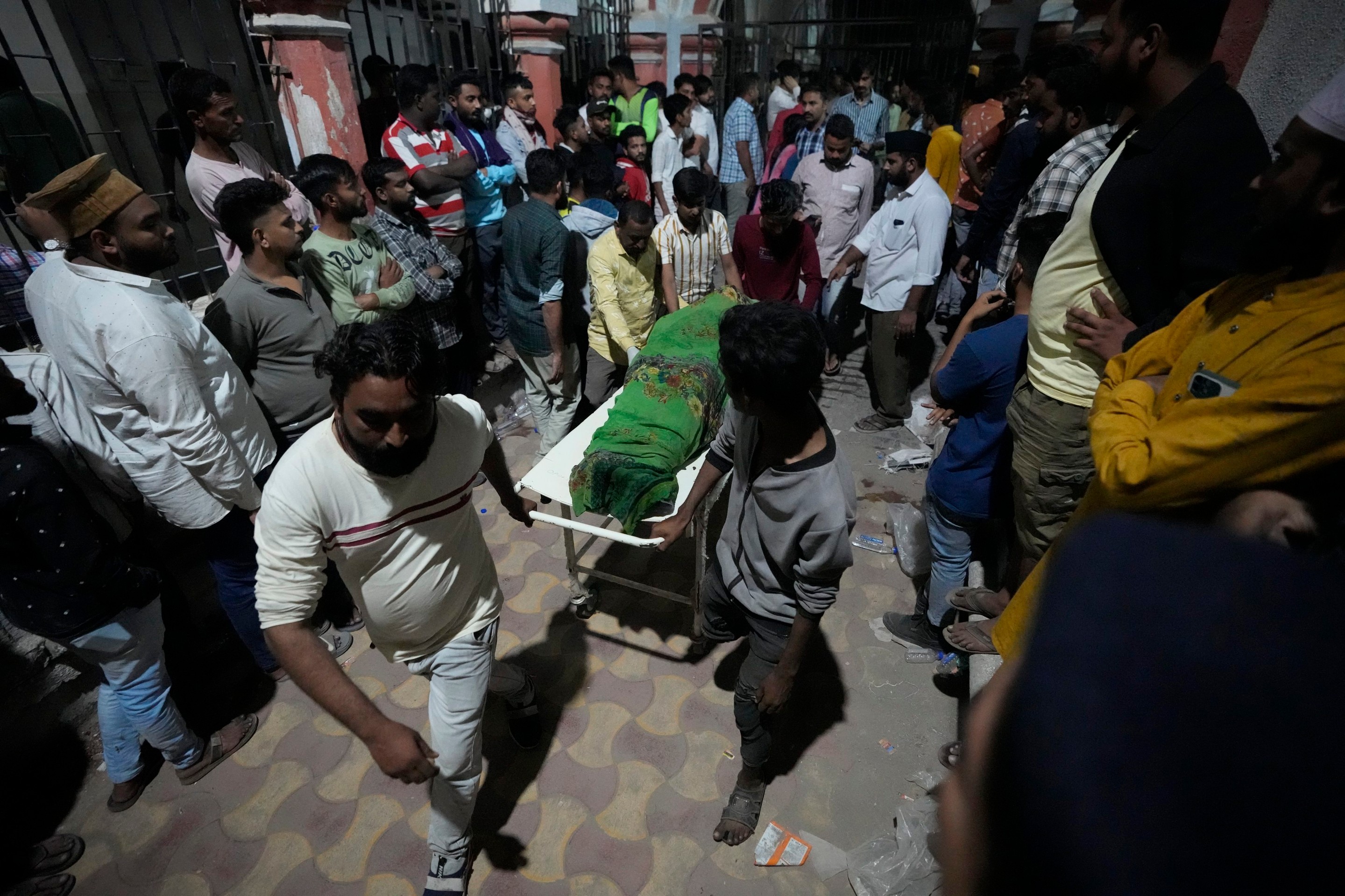 Dobrovoľníci a záchranári odnášajú obete zrúteného mosta v Indii.