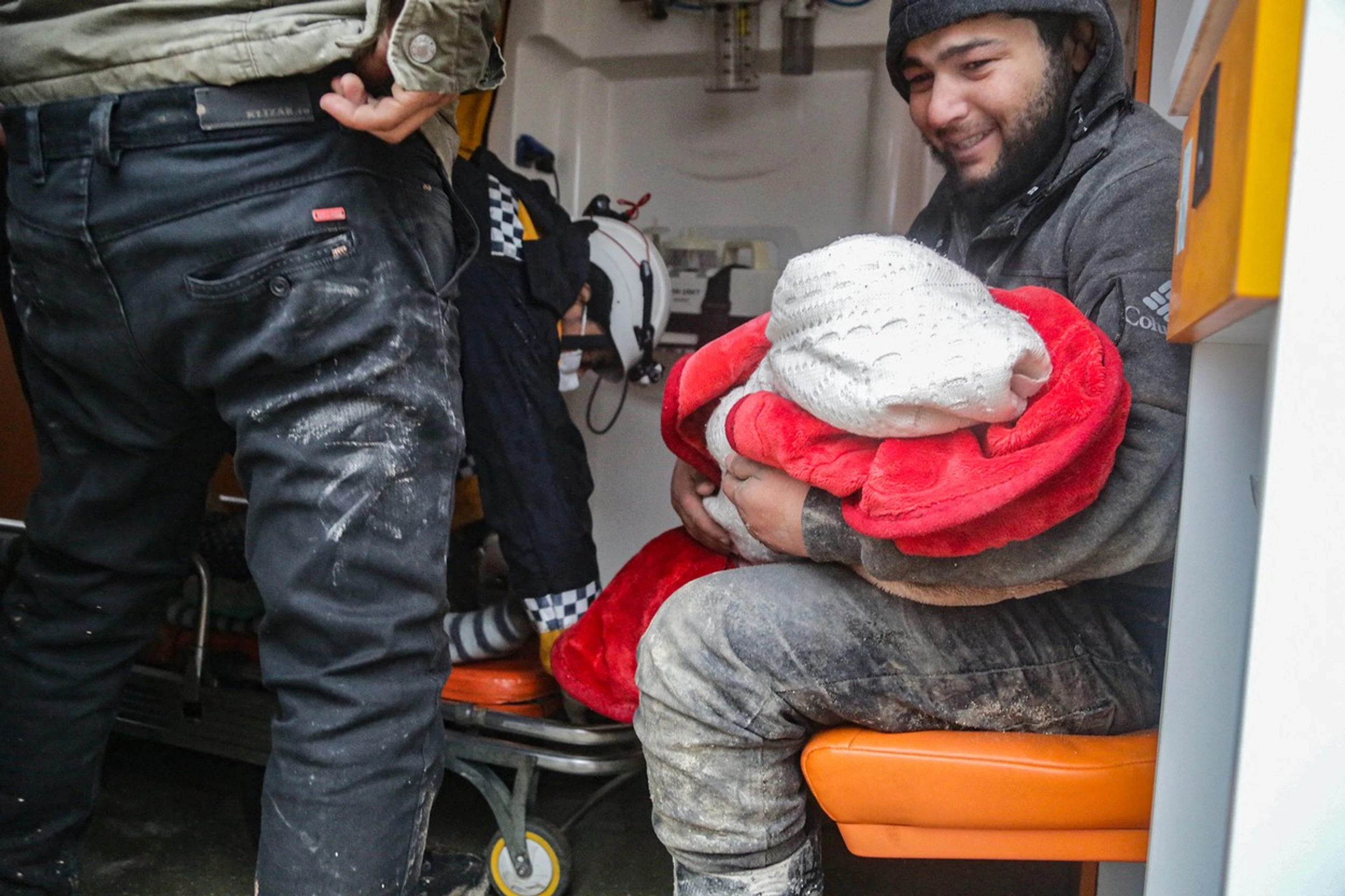 Muž drží v náručí dieťa po zemetrasení v sýrskom Aleppe.