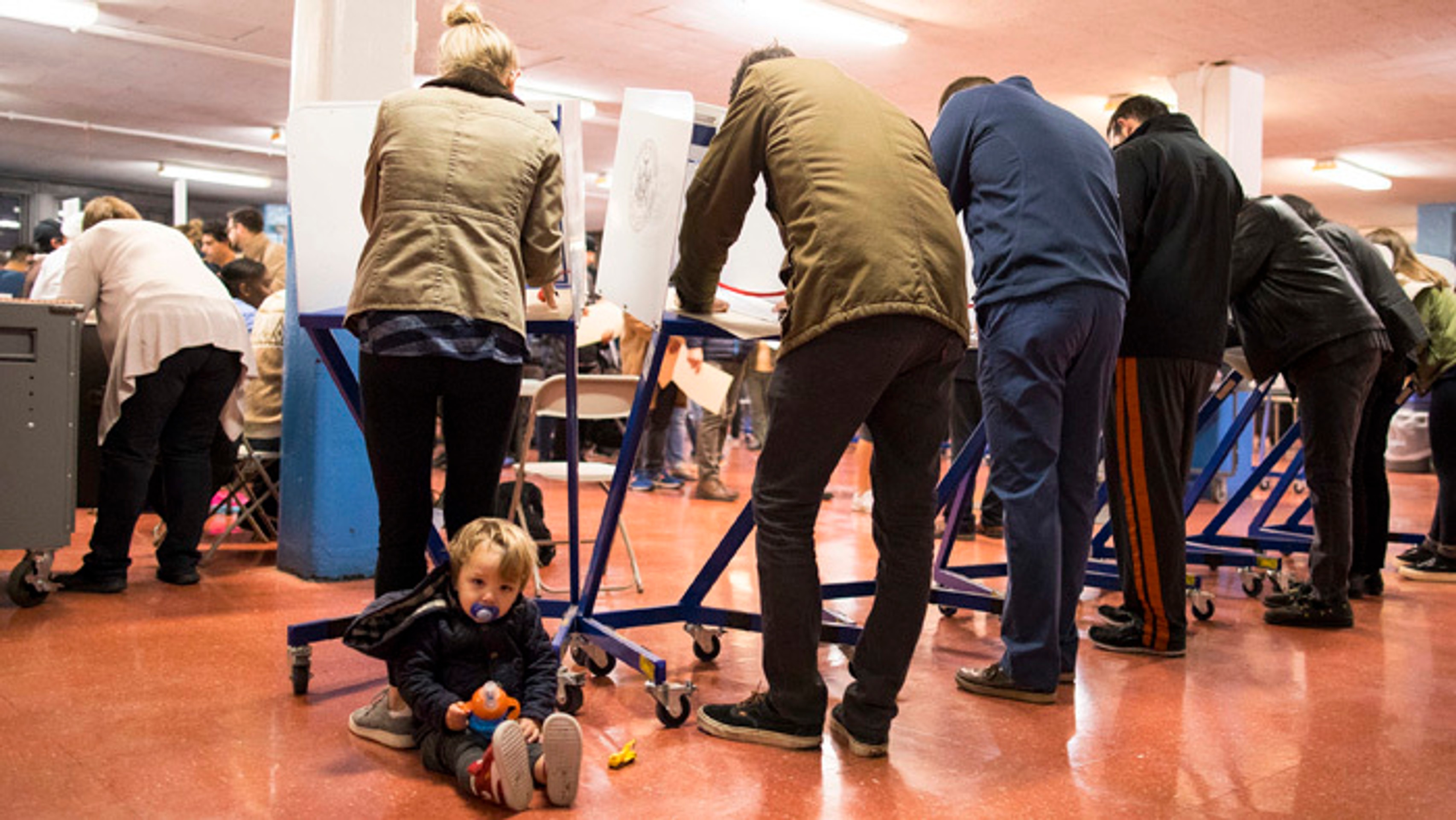 Dieťa sedí a čaká kým mamička vo volebnej miestnosti v Brooklyne v New Yorku vyplní hlasovací lístok. 