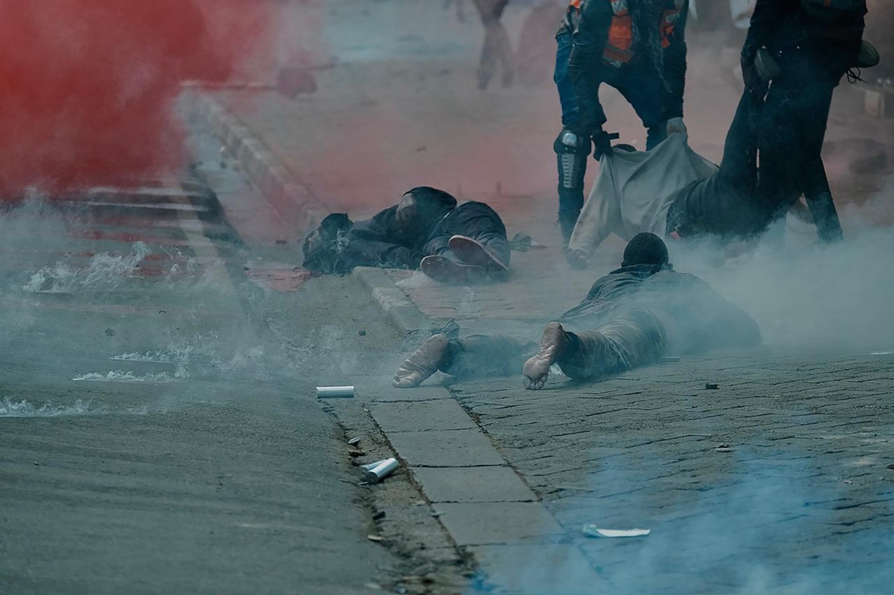 Zranení demonštranti ležia na hodníku po zásahu polície.
