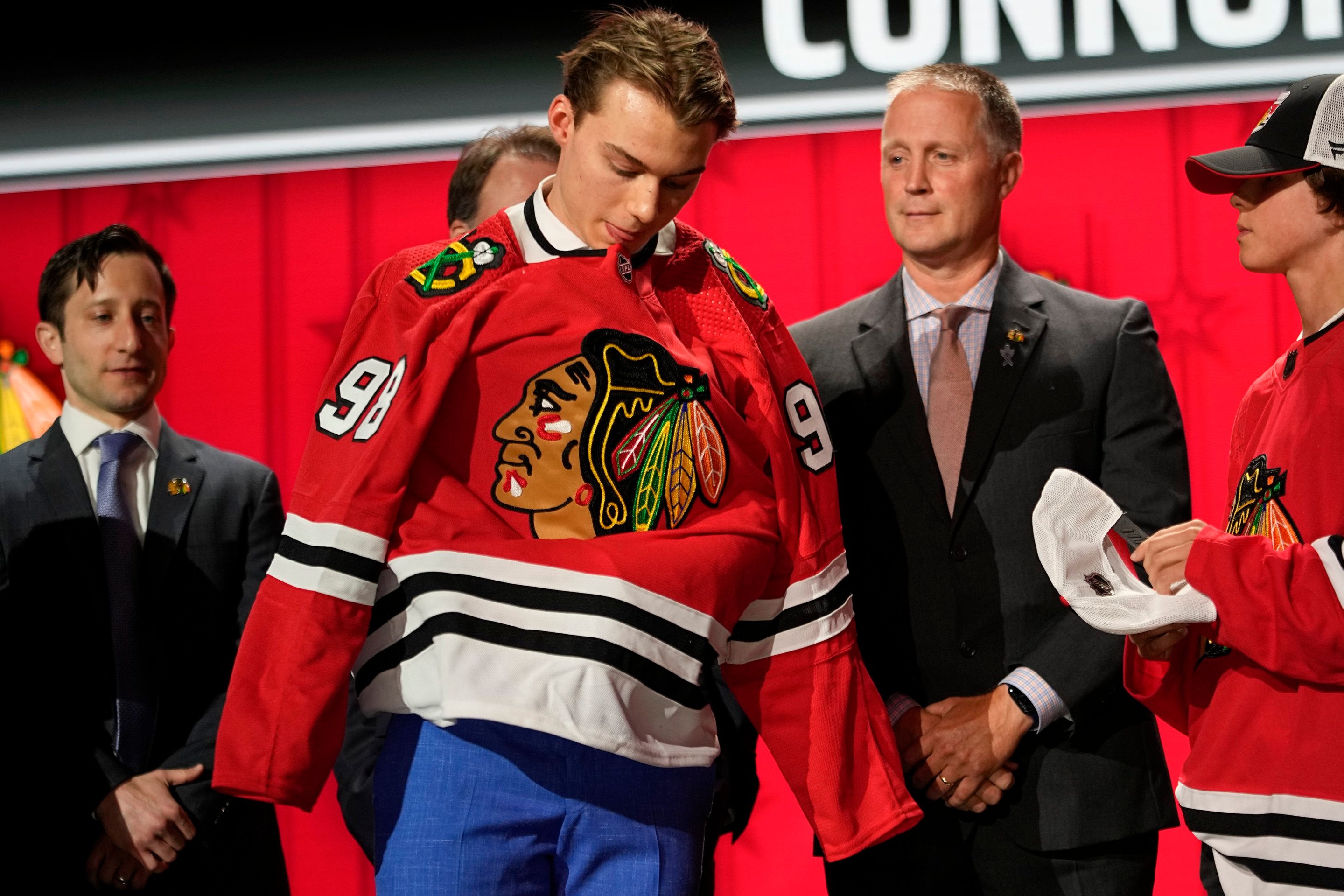 Connor Bedard si oblieka dres Chicaga na NHL drafte 2023.