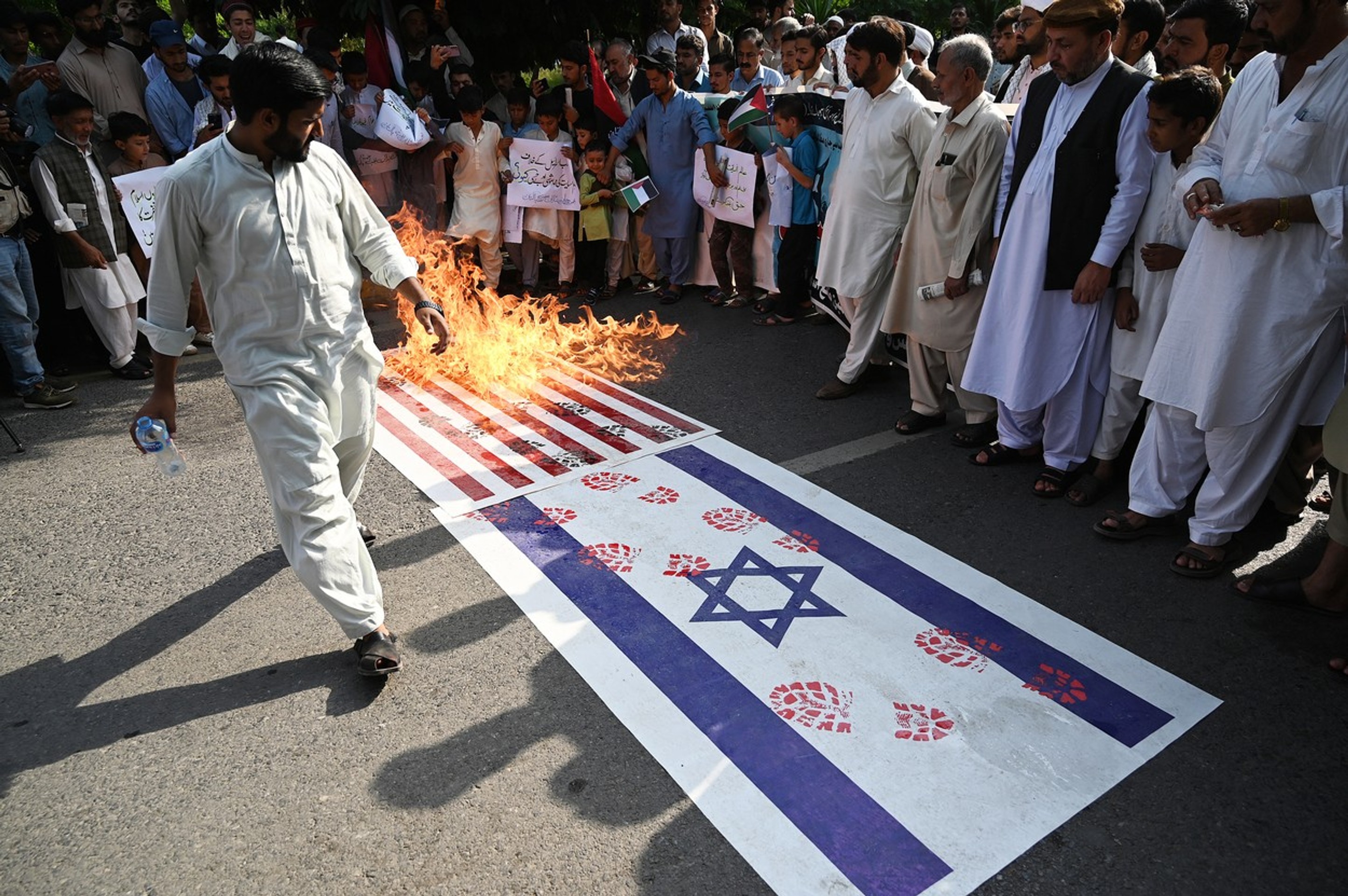 Pálenie izraelskej a americkej vlajky na protestnom zhromaždení v pakistanskom Islamabáde.