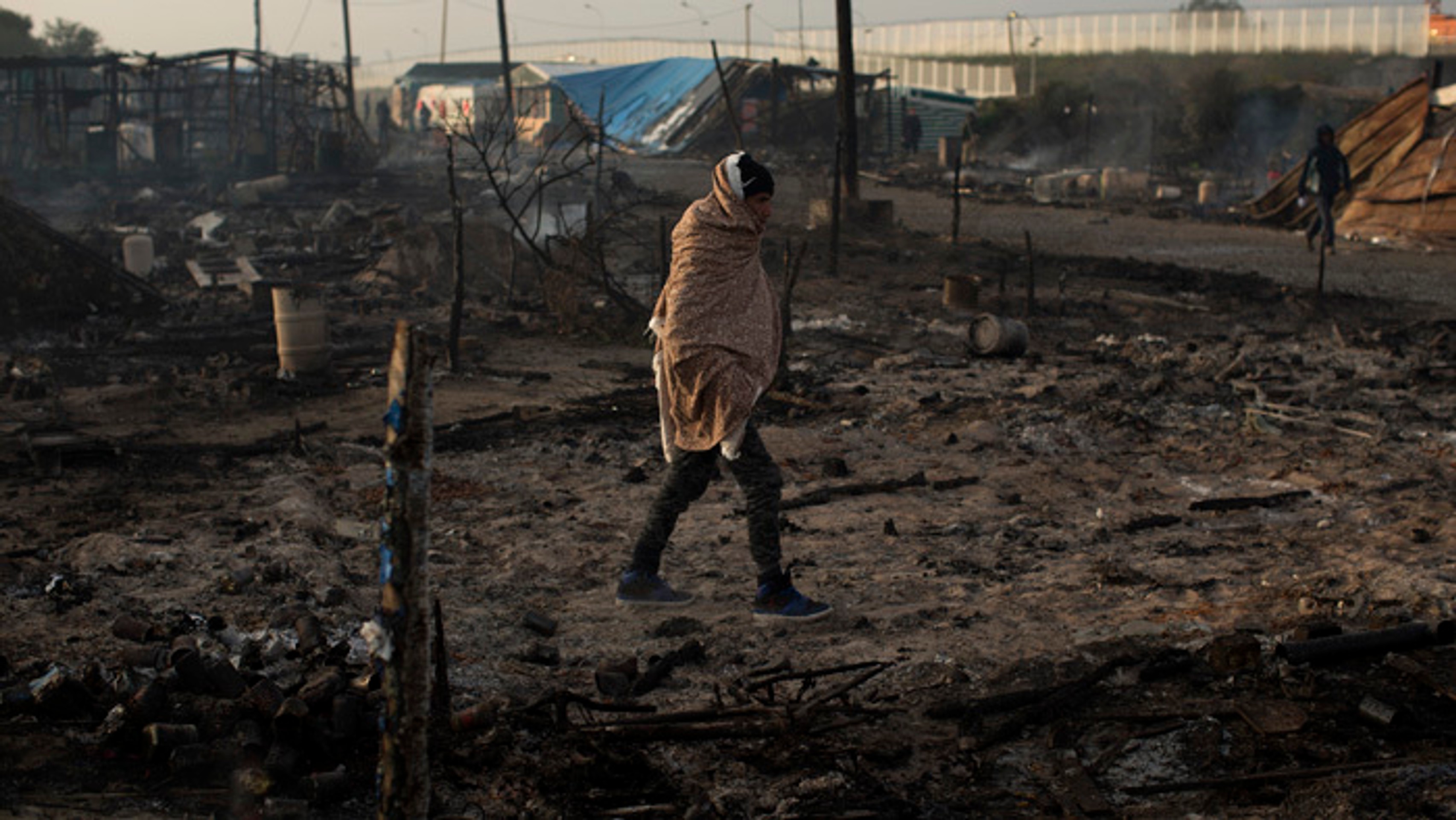Migranti opúšťajú tábor v Calais.