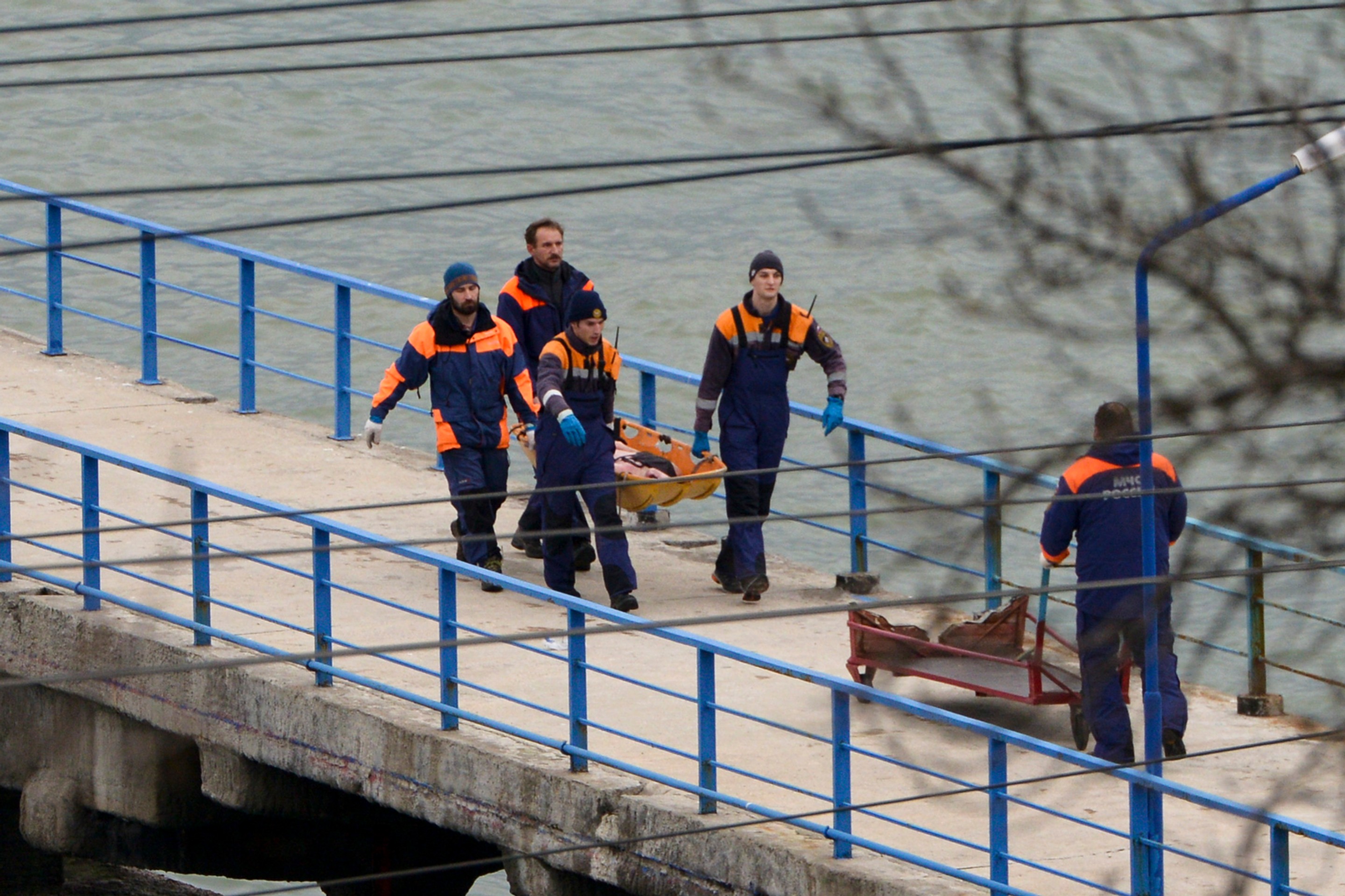 Ruskí záchranári nesú telo z vraku zrúteného lietadla typu Tu-154 na móle neďaleko Soči.