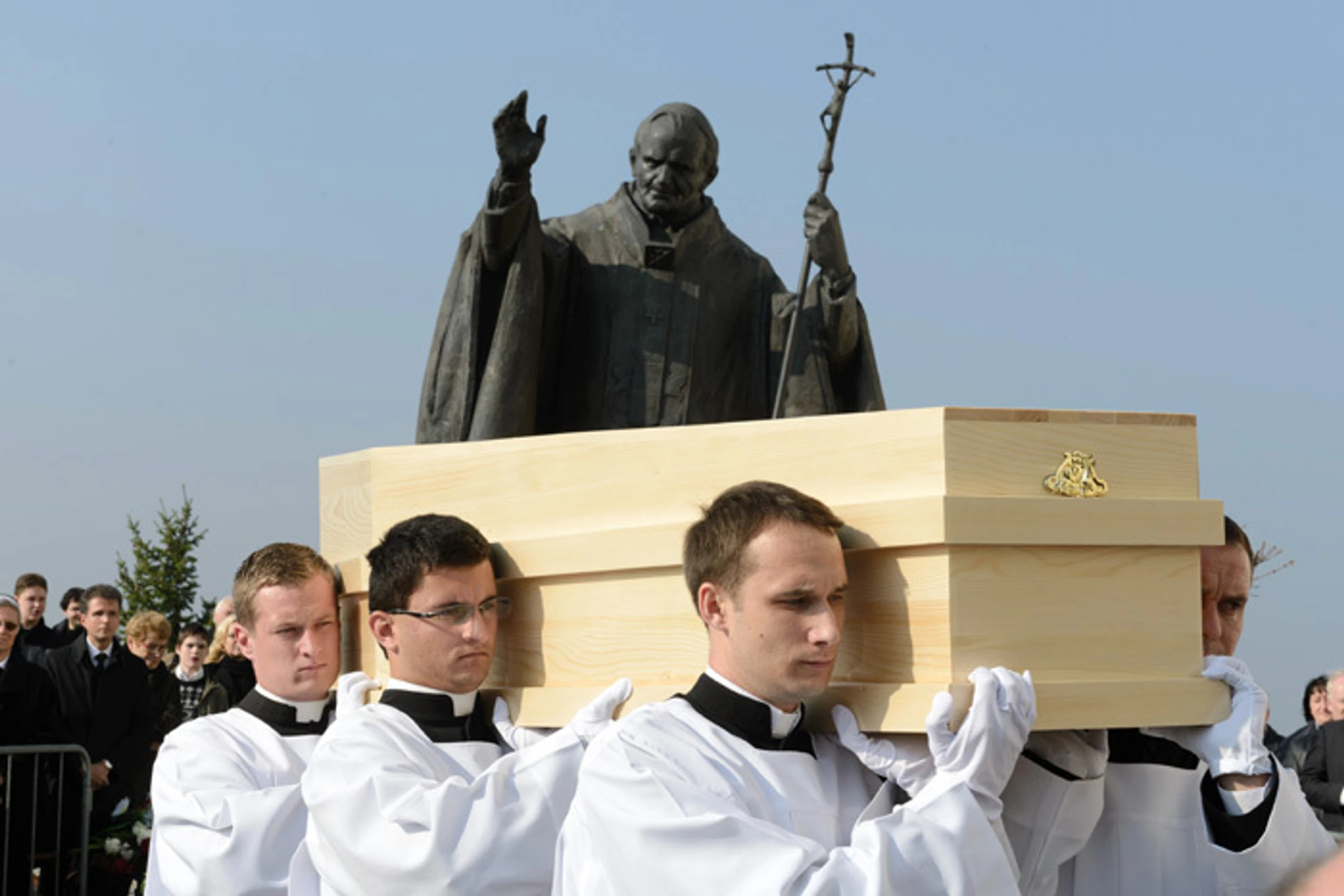 Seminaristi nesú truhlu s pozostatkami kardinála Jána Chryzosta Korca okolo sochy  Jána Pavla II.