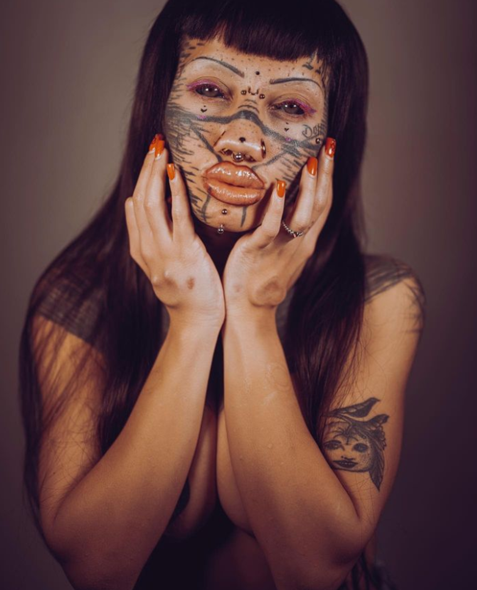 Tvár má plnú piercingov a tetovaní