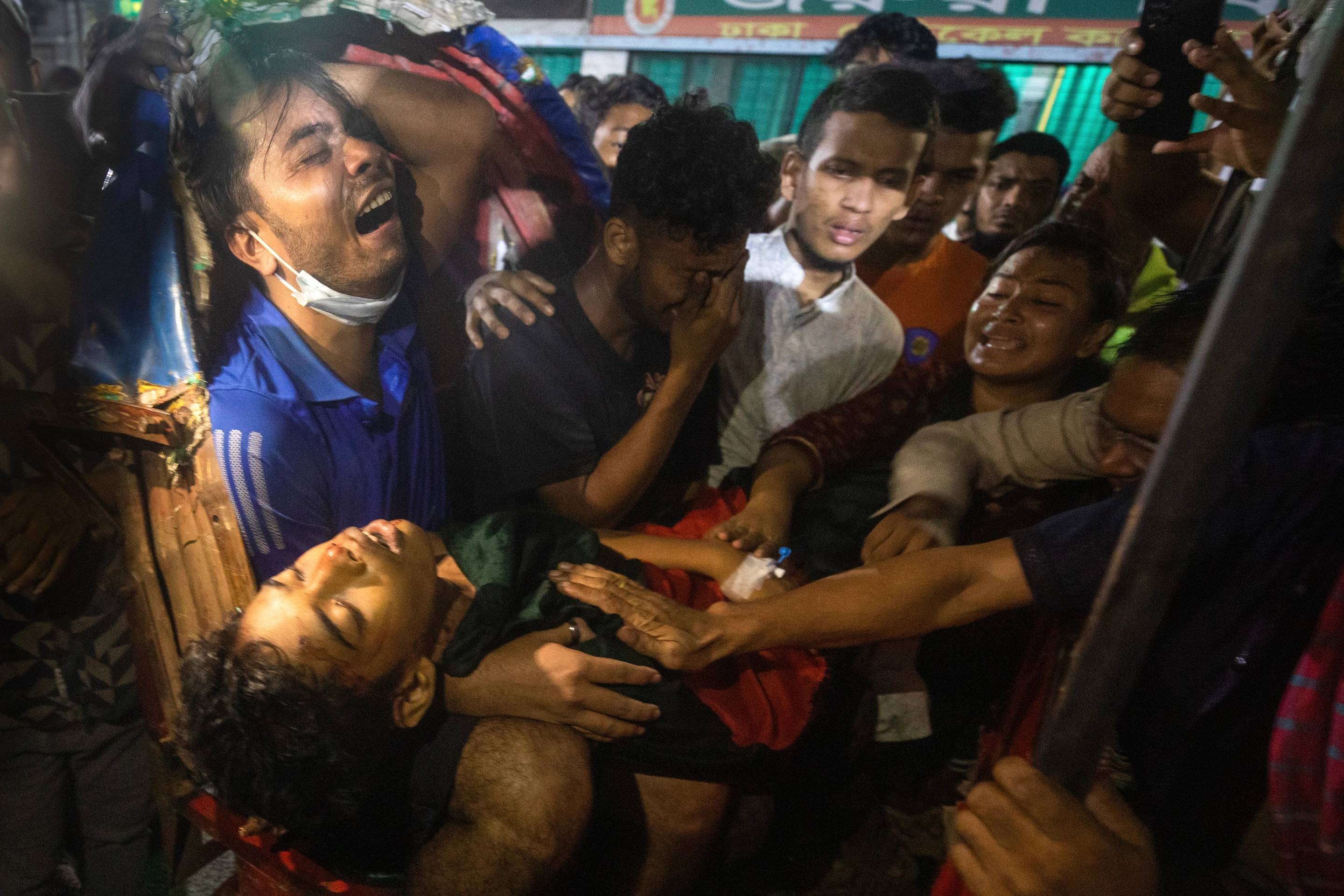Na snímke muži plačú nad mŕtvym telom muža, ktorý bol zabitý na protivládnych protestoch v Bangladéši.